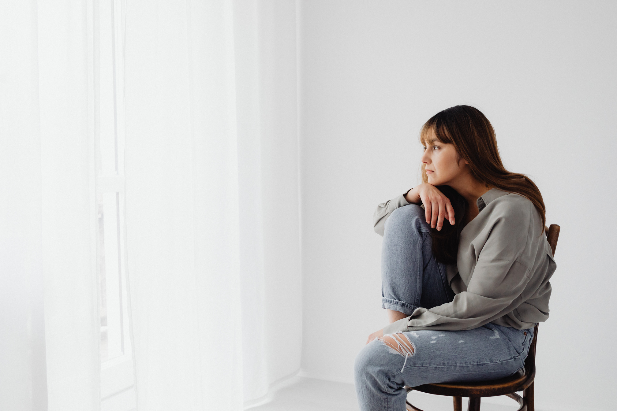 A Woman in Gray Long Sleeves Sitting on Chair Looking Pensive